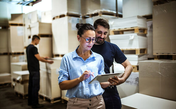 Warehouse workers searching on a tablet for logistics IT solutions