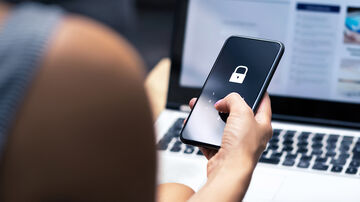 IT security A woman holds a smartphone that requires a PIN code, symbolizing end-point protection using T Business IT Security solutions.