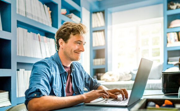 Smiling man using laptop with SD-WAN for remote work | T Business