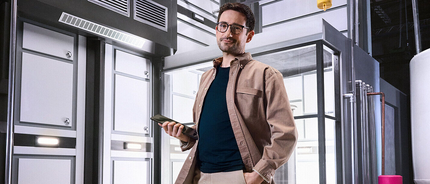 Cloud Computing and connectivity solutions A business man standing casually in his company building with one hand in his pocket and with a tablet in his other hand, knowing everything runs smoothly because of cloud and connectivity solutions from Telekom Business Europe.