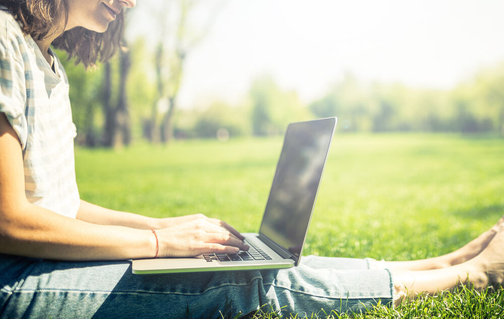 Remote Working Solutions A person working on her laptop in the park thanks to remote working solutions
