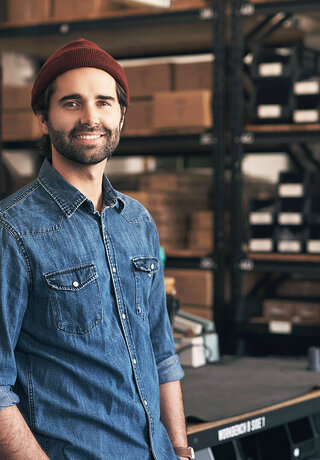 A man standing in a workshop smiling because he can rely on T Business Europe's digitalization solutions for a new website or webshop.