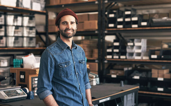 A man standing in a workshop smiling because he can rely on T Business Europe's digitalization solutions for a new website or webshop.
