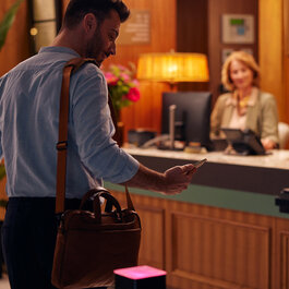 Man holding his smartphone for digital communication in a hotel.