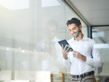 A man holding a tablet and looks happy about the best service and support from the T Business Microsoft Azure experts.