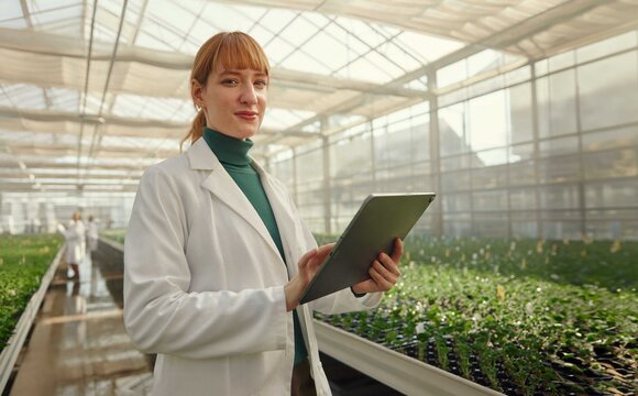 A young women searching on her tablet for connectivity solutions in a green house | T Business