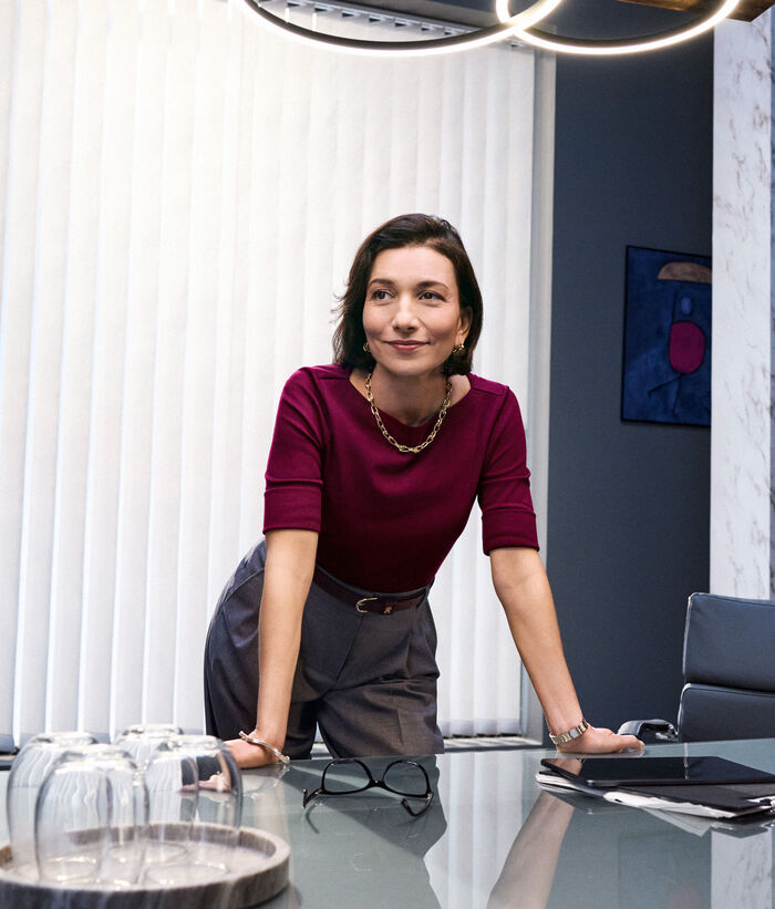 Small business IT security solutions A business woman leans confidently on her desk in her office because she knows that her business is safe with IT security solutions from Telekom Business Europe.
