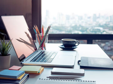 New work A laptop and a smartphone on a desk in a modern apartment, a digital workplace with new work solutions by T Business.