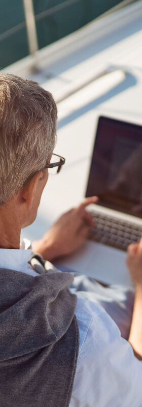 New work A man works with his laptop on a sailing boat with the new work solutions for digital workplaces from T Business.