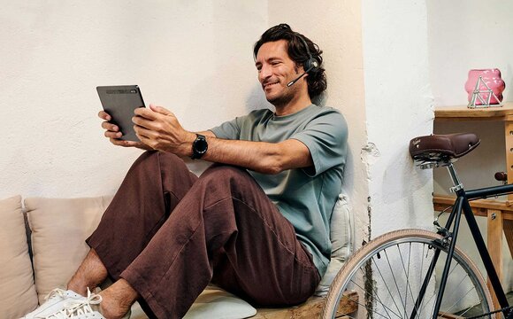 A man wearing a headset searching for ICT solutions in Europe on his tablet