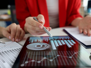 Business women studying charts on tablet visualizing data driven marketing solutions with big data analytics by T Business.