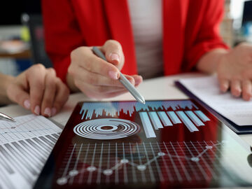 Business women studying charts on tablet visualizing data driven marketing solutions with big data analytics by T Business.