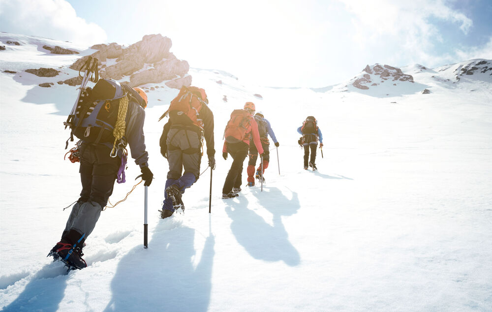Cloud Computing Mountaineers on a snowy slope follow a guide and symbolize the guidance in the cloud journey with cloud computing from T Business.