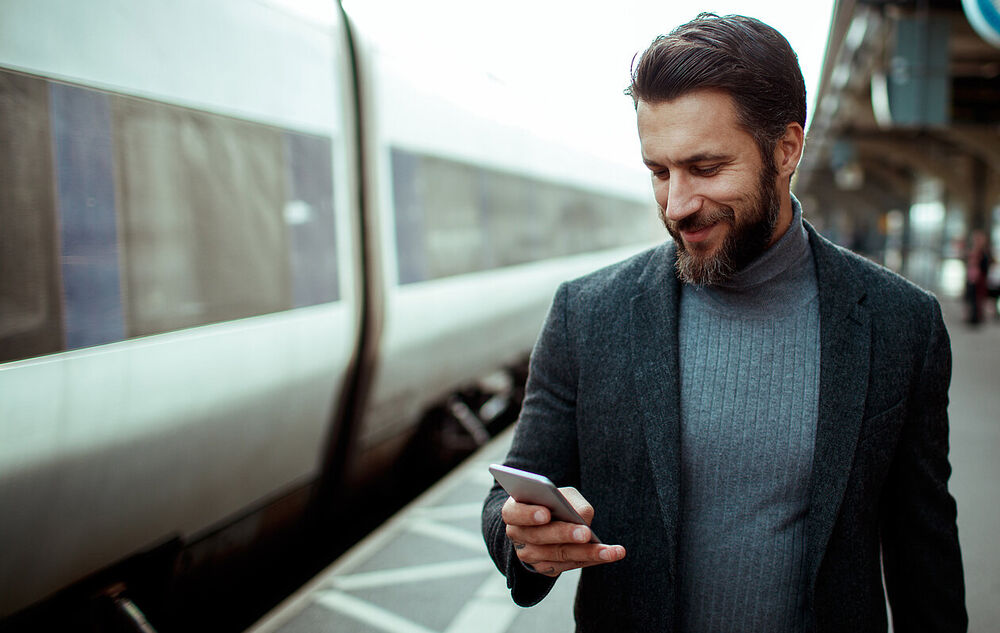 Cloud Computing A businessman looks at his smartphone with a smile while using cloud-native cloud computing apps from T Business.