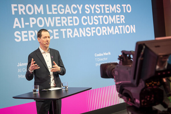 AI Customer Service János Horváth Varga speaks on stage in front of a screen titled "From Legacy Systems to AI-Powered Customer Service Transformation" during the Mobile World Congress (MWC) 2026.