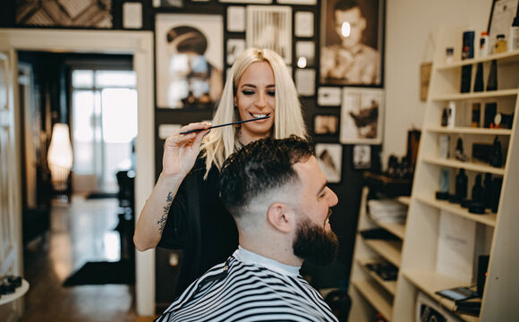 A hairdresser serving a customer and thinking about digitalization of her SMB