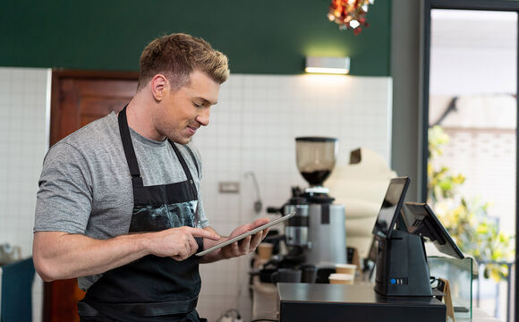 A barista using digital tablet looking for digitalization solutions