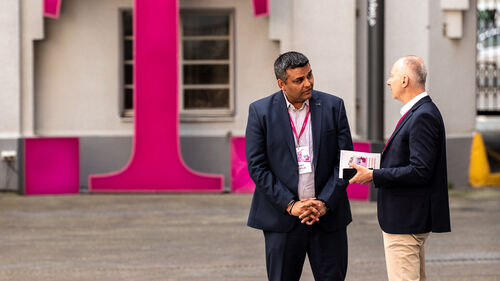 Digital Transformation in Banking & Insurance Industry Men talking in front of the T Business logo at Digital Transformation in Banking & Insurance Industry