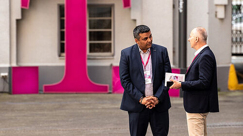 Digital Transformation in Banking & Insurance Industry Men talking in front of the T Business logo at Digital Transformation in Banking & Insurance Industry