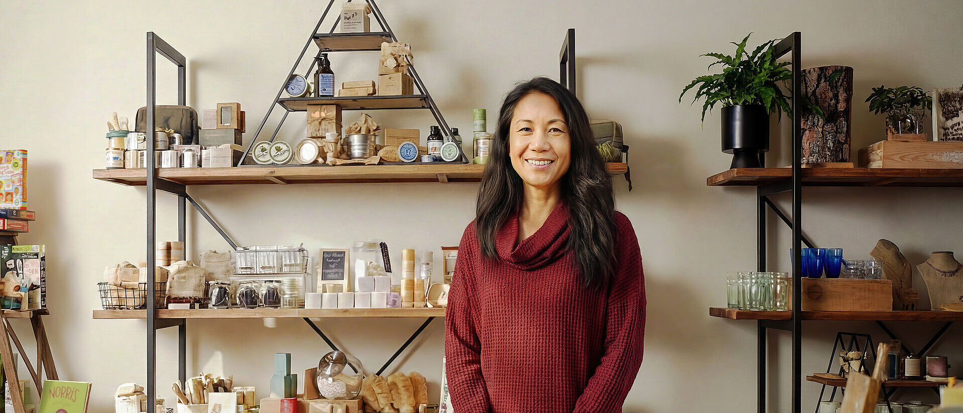 Small Business IT Solutions A woman stands in front of shelves stocked with high-quality natural products, such as cosmetics, which she sells through her online shop.