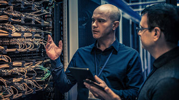 Remote Working Solutions An IT engineer with a digital tablet explaining to his supervisor the server configuration and operation necessary for remote working solutions