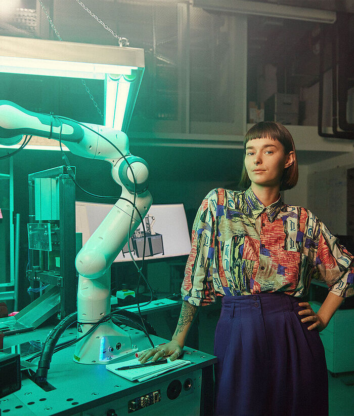 IoT Ecosystem A woman stands in a laboratory; next to her is a modern robotic arm.