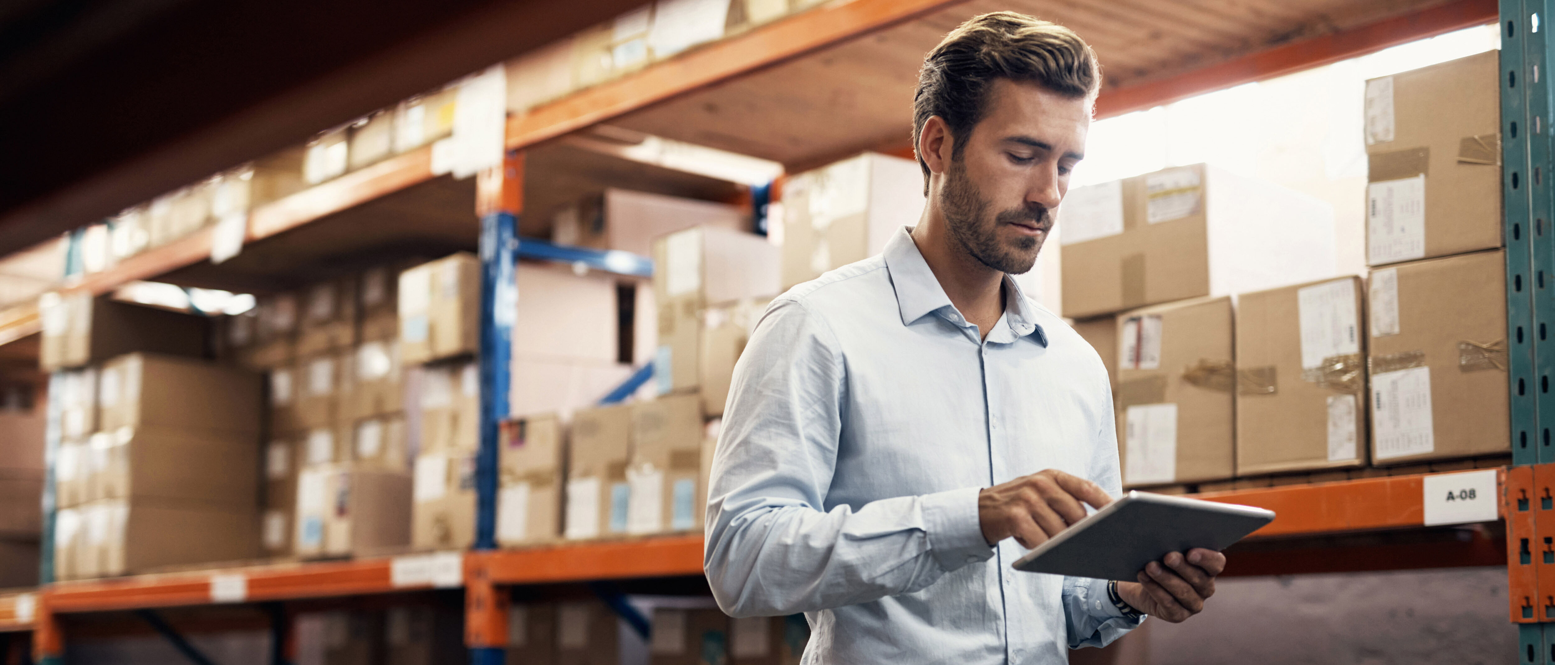 Connectivity solutions A business man works with a tablet in a warehouse setting, showcasing connectivity solutions by T Business.