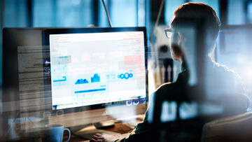 Secure Connectivity A businessman works on a computer and uses T-Business secure connectivity solutions.