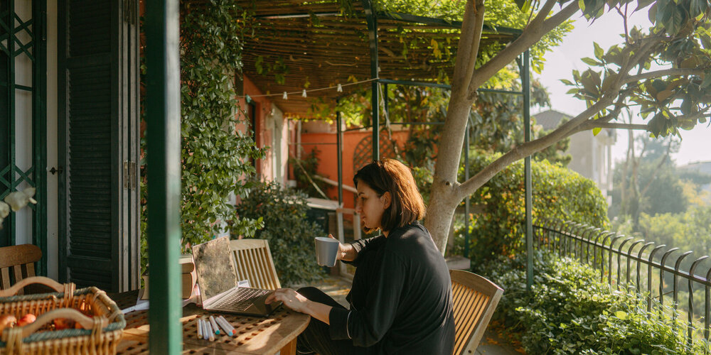 A young woman is working on her laptop on her garden terrace.