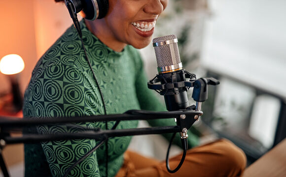 A woman sitting in front of a microphone and doing a podcast to the one from T Business and COSMOTE.