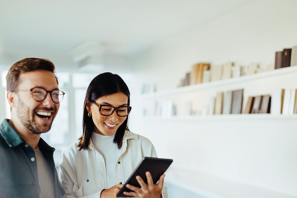Small Business IT solutions Business woman standing with her colleague using the T Business communication plattform on her tablet.