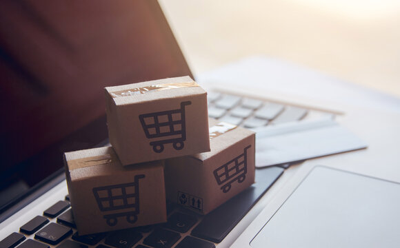 Paper cartons with a shopping cart logo on a laptop that's searching for logistics IT solutions | T Business