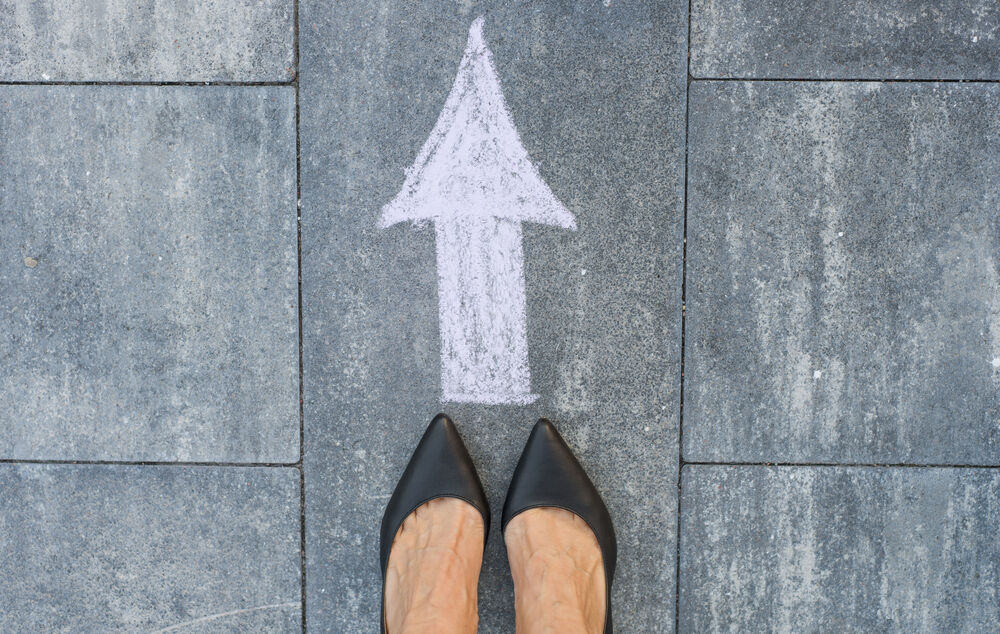 IT security A pair of shoes stands in front of an arrow on a road, symbolizing how IT security solutions from T Business can ensure business continuity.