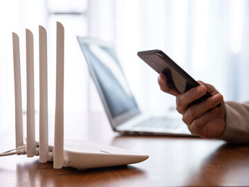 Hospitality IT Solutions A person searching for hospitality IT solutions on their smartphone while sitting in front of a router