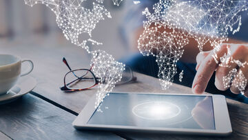 Fast internet connection A tablet is positioned on a table and connected to the stylized communication network depicted above it to illustrate the fast internet connection by T Business.