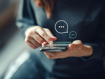 Application modernization A woman holding her smart phone and communicates easily through application modernization from T Business.