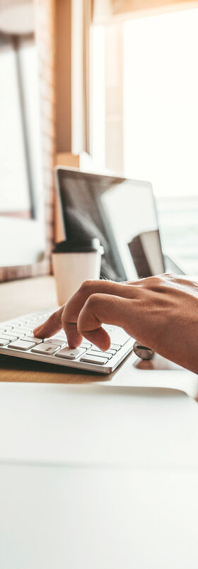 Secure Connectivity A man is working on a computer, next to him are laptops, all connected with secure connectivity services by T Business.