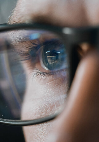 A man with glasses reflecting the laptop search for security solutions