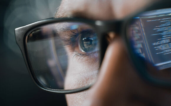 A man with glasses reflecting the laptop search for security solutions