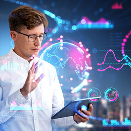 A man in a white shirt and glasses with a tablet in his left hand. With his right hand, he projects a fluorescent globe over the tablet and numerous other fluorescent numbers and statistics surround him.