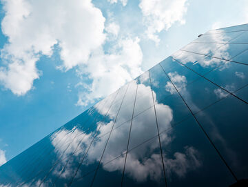 Cloud readiness Clouds are reflected in a skyscraper symbolizing full infrastructure assessment with cloud readiness, a T Business solution.