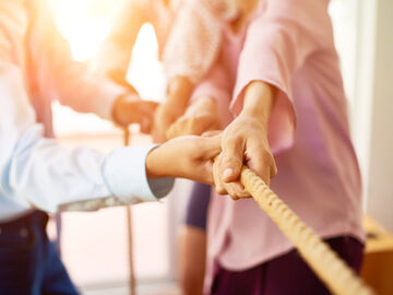 A team pulling rope together symbolize working together with next generation hybrid data center, a solution of T Business.