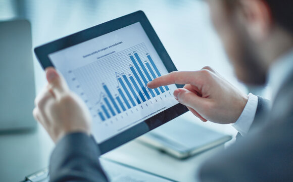 Human hand pointing at financial chart on digital tablet using SD-WAN | T Business