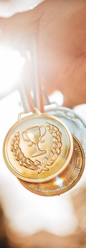 Application modernization Gold medals are held up visualizing the success with application modernization from T Business.