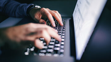 Business IT security A man works on a laptop with log management tools, business IT security solutions from T Business.