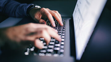 Business IT security A man works on a laptop with log management tools, business IT security solutions from T Business.