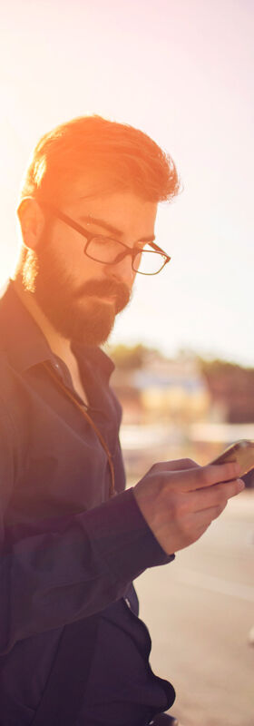 Fast internet connection A man is using his smartphone in a city at dusk and is able to access the mobile internet at high speeds thanks to the fast internet connection by T Business.