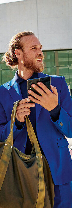 Small Business Communication Platform Two business man in suits outside of a building and one holding a smartphone looking like they are searching for something.