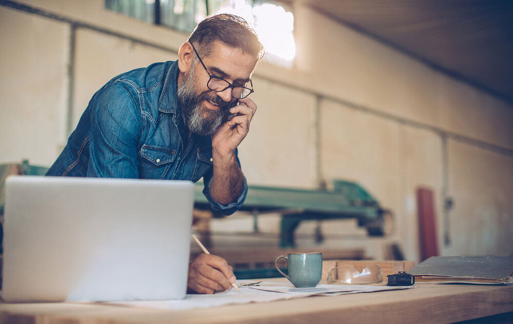 Small Business IT Solutions | T Business A man working with his laptop in front of him talking in his phone about small business IT solutions