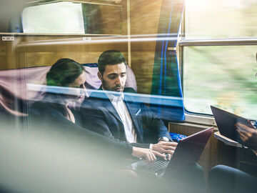 New work Three business people working with their laptops together in a train with the new work solutions for digital workplaces by T Business.